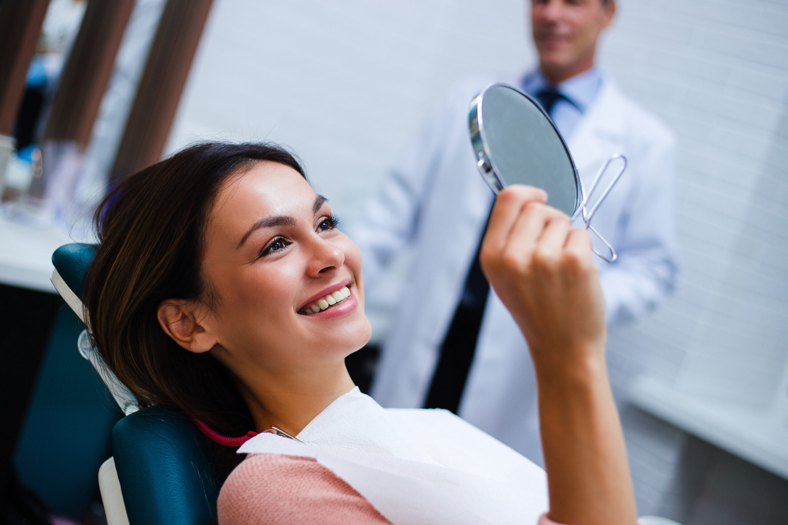 A relaxed young woman in a dental exam chair observing her teeth whitening results.